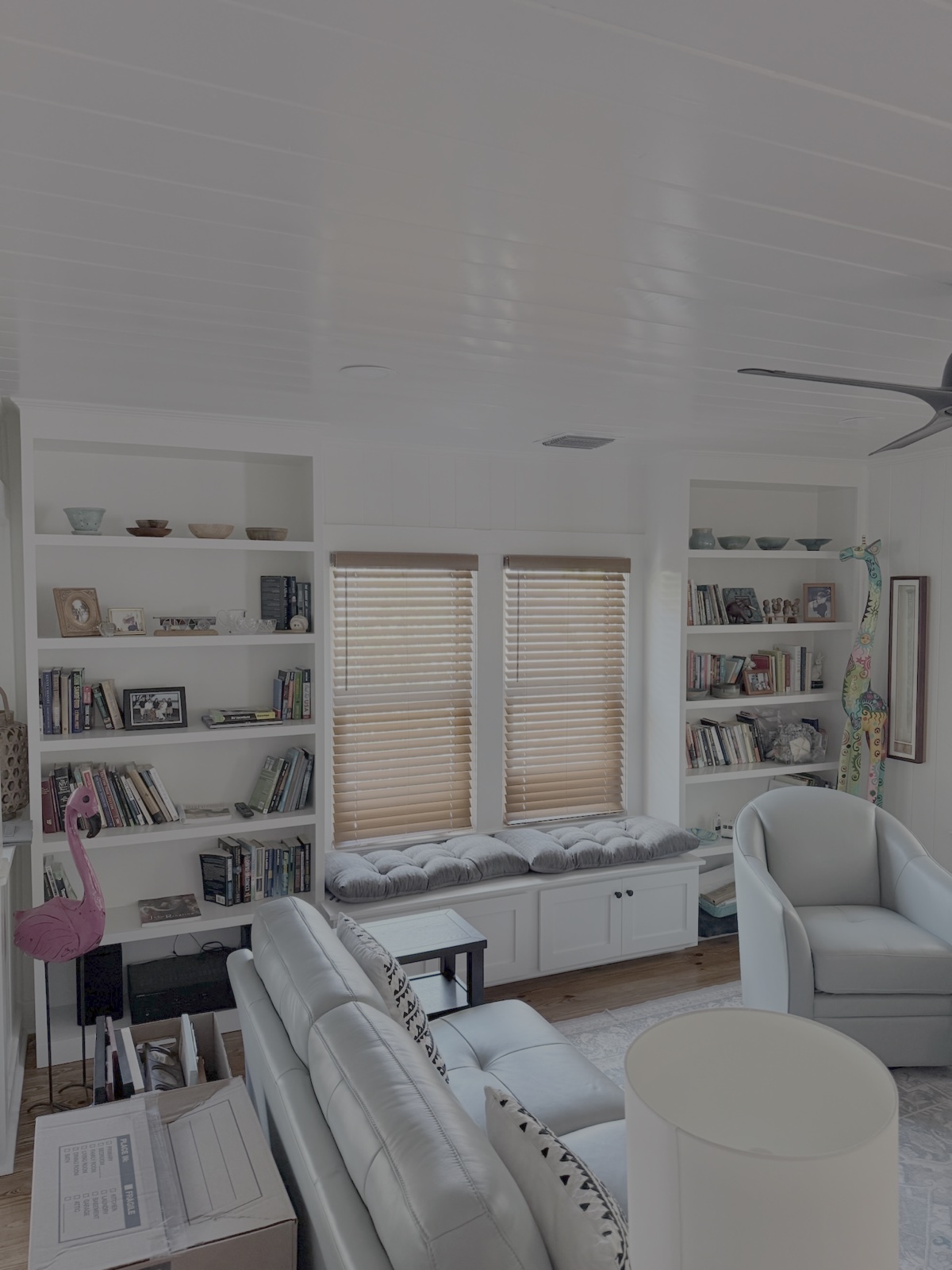Custom painted floor-to-ceiling living room shelving and window bench built-in wall in Lakewood Ranch FL