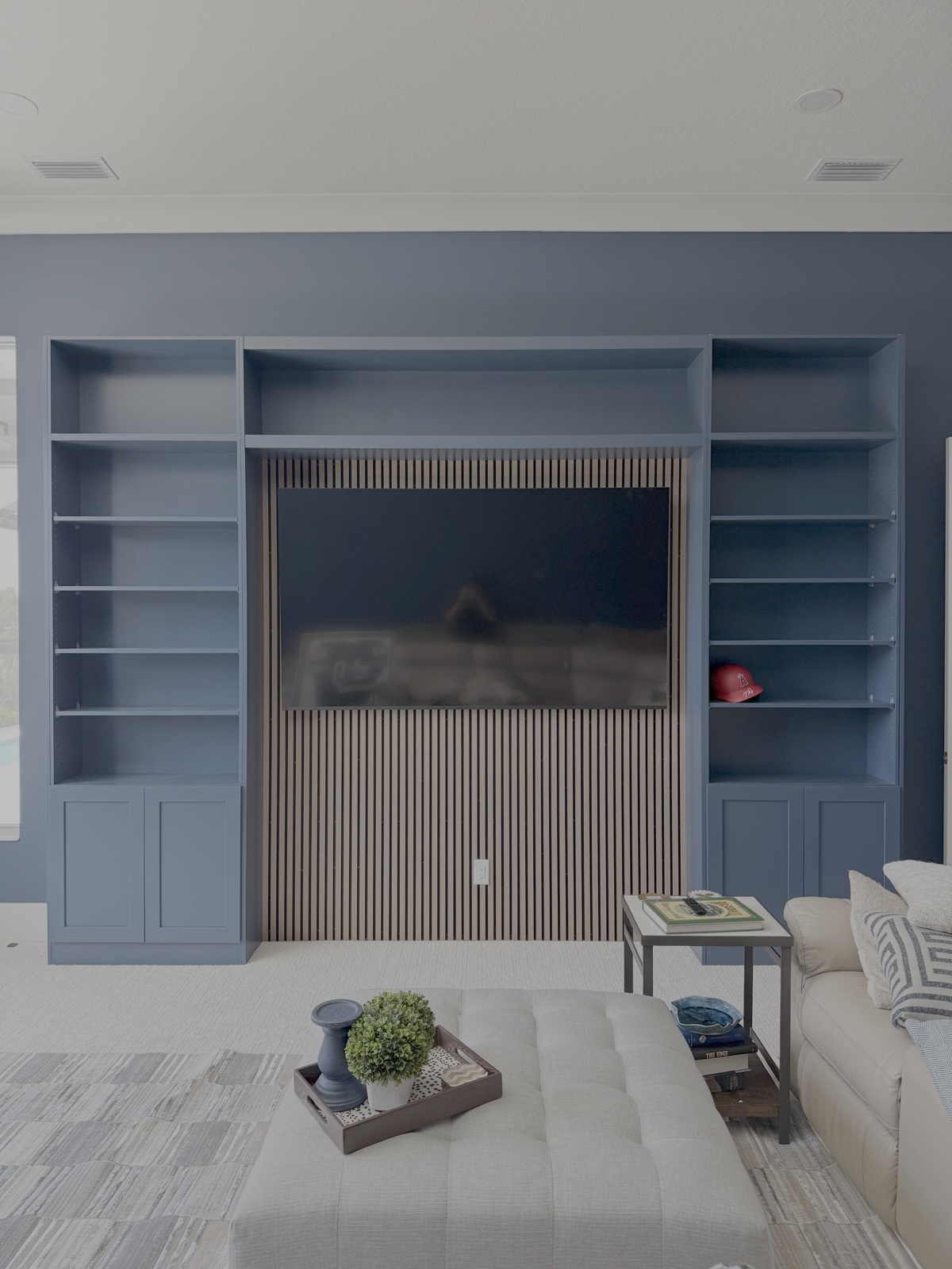 Custom navy blue built-in media center cabinetry with natural wood slat TV backdrop in Lakewood Ranch