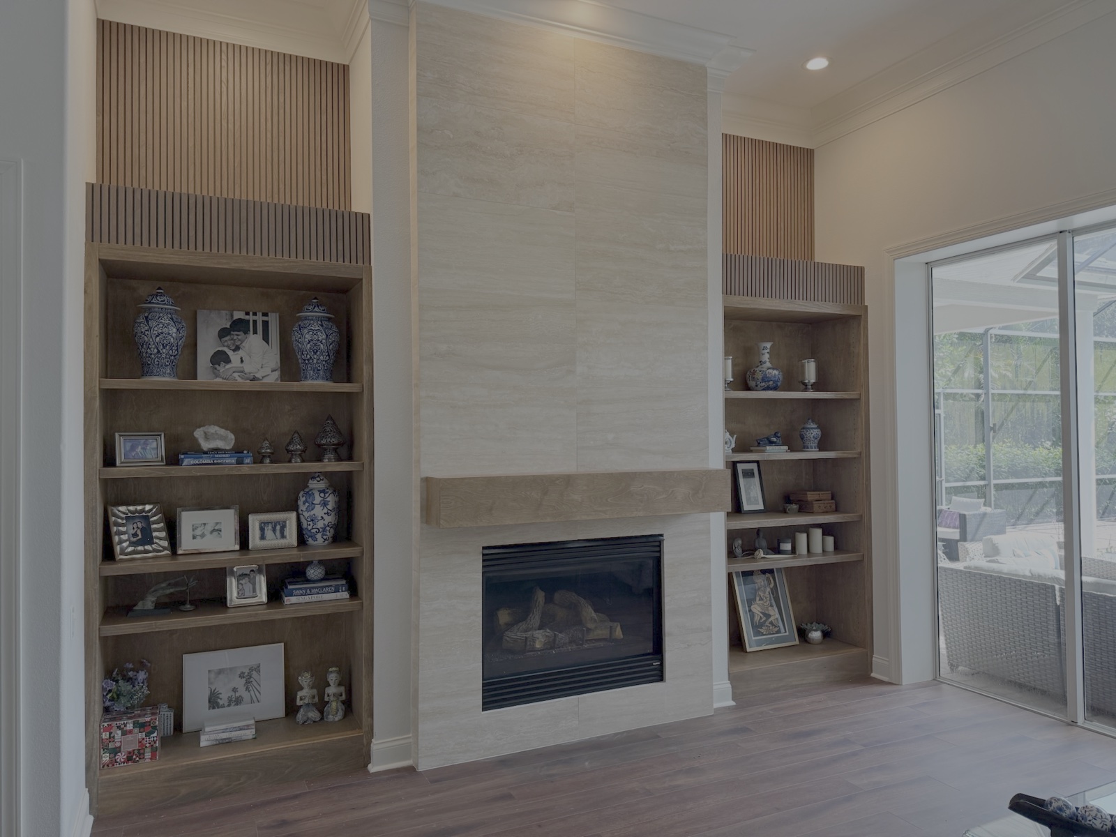 Modern stone slab fireplace surround with solid timber floating mantle and wood slat accents in Manatee County FL